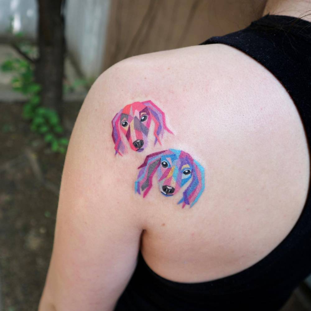 Pop art style Dachshund portraits tattooed on the shoulder blade.