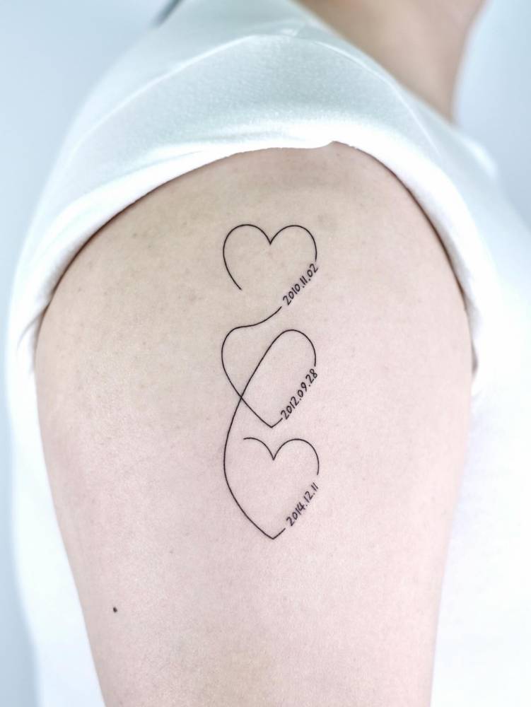 Hearts and dates tattoo located on the shoulder.