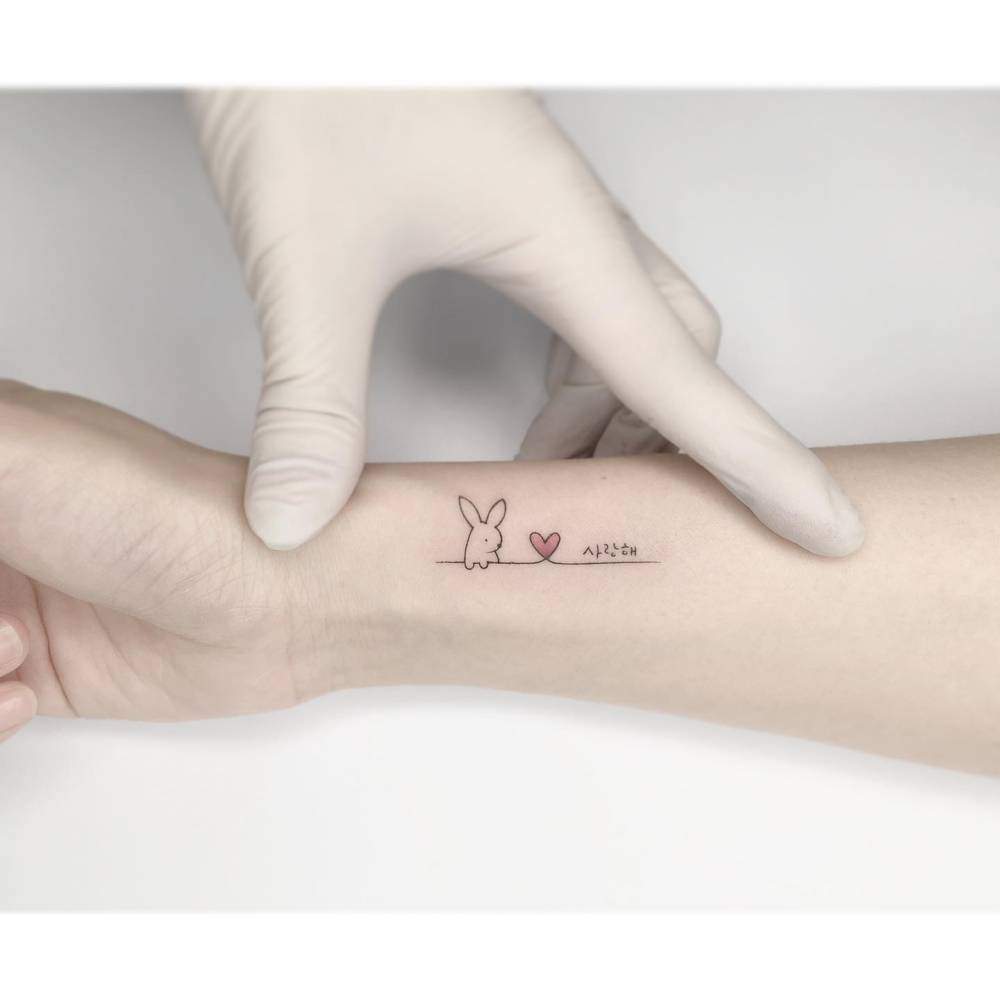 Minimalistic style bunny and heart tattoo located on the wrist.