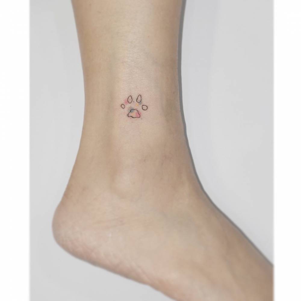 Little dog paw print tattoo located on the ankle.