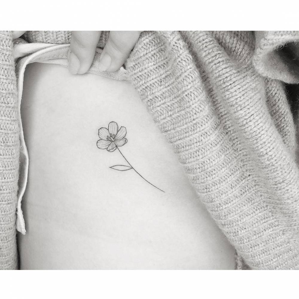 Fine line style flower tattoo placed on the side boob.