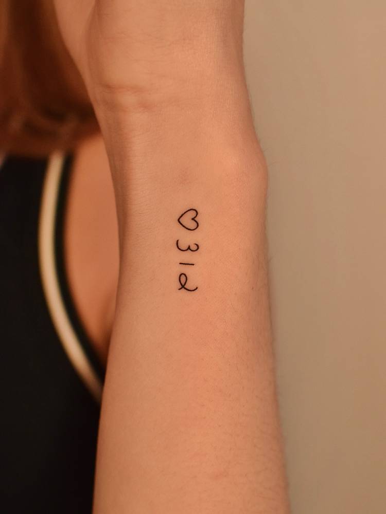 Number "312" and minimalistic heart tattooed on the wrist.