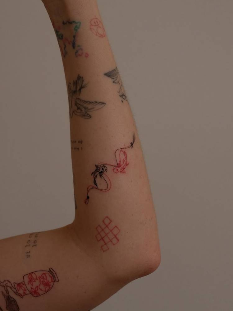 Two opposite fish tattoo placed on the inner forearm, fine line style.