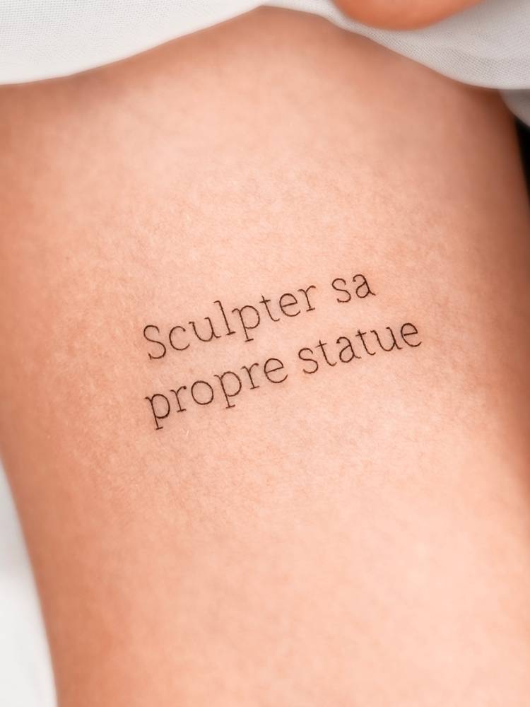 "Sculpter sa propre statue" lettering tattoo in typewriter font.