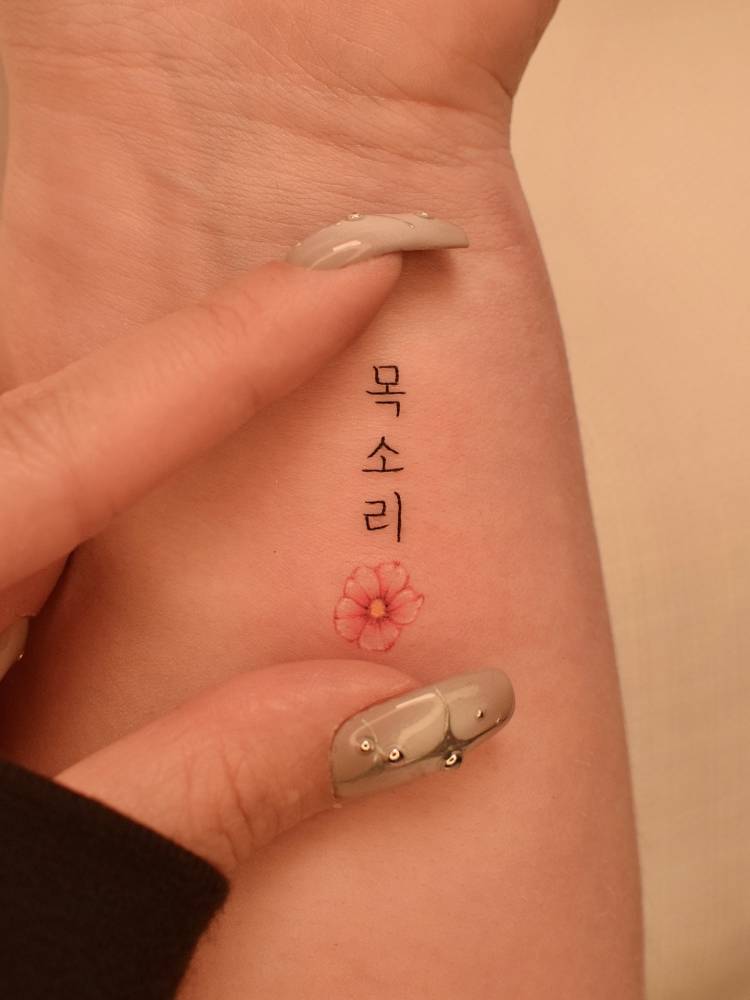 Korean lettering and cherry blossom tattoo located on the wrist.