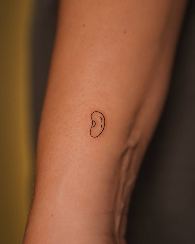 Tiny minimalistic bean tattoo located on the wrist.