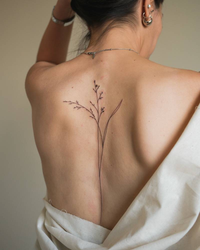 Floral design tattooed on the spine, done in fine line style.