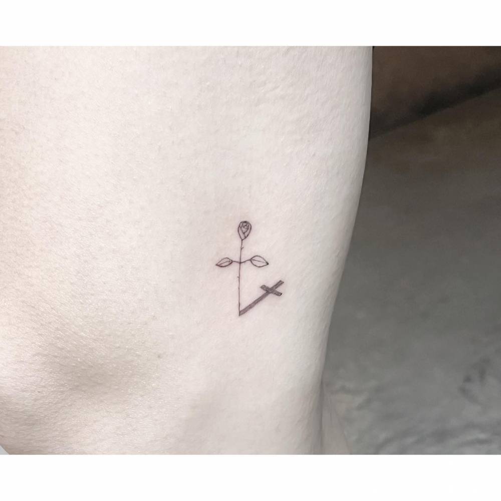 Minimalistic style rose and cross tattoo located on the inner arm.