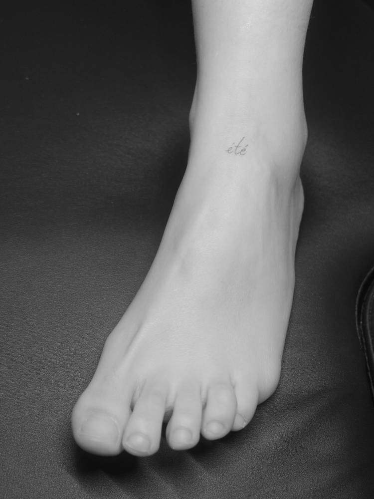 "Été" lettering tattoo in handwritten font located on the foot.