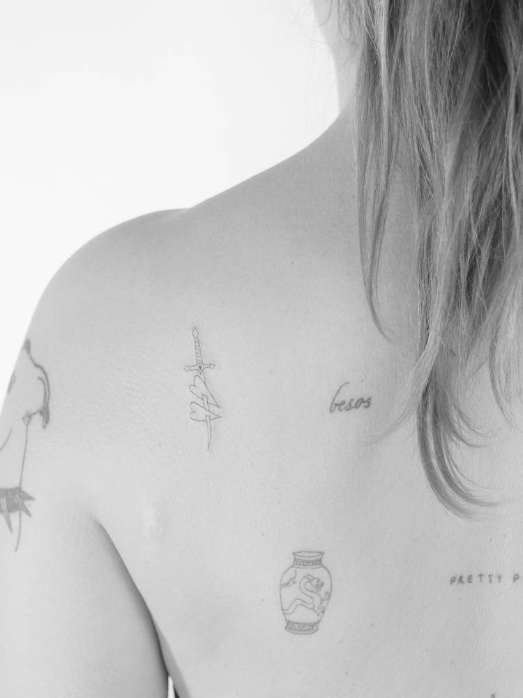 Hearts and dagger tattooed on the shoulder blade, done in fine line style.