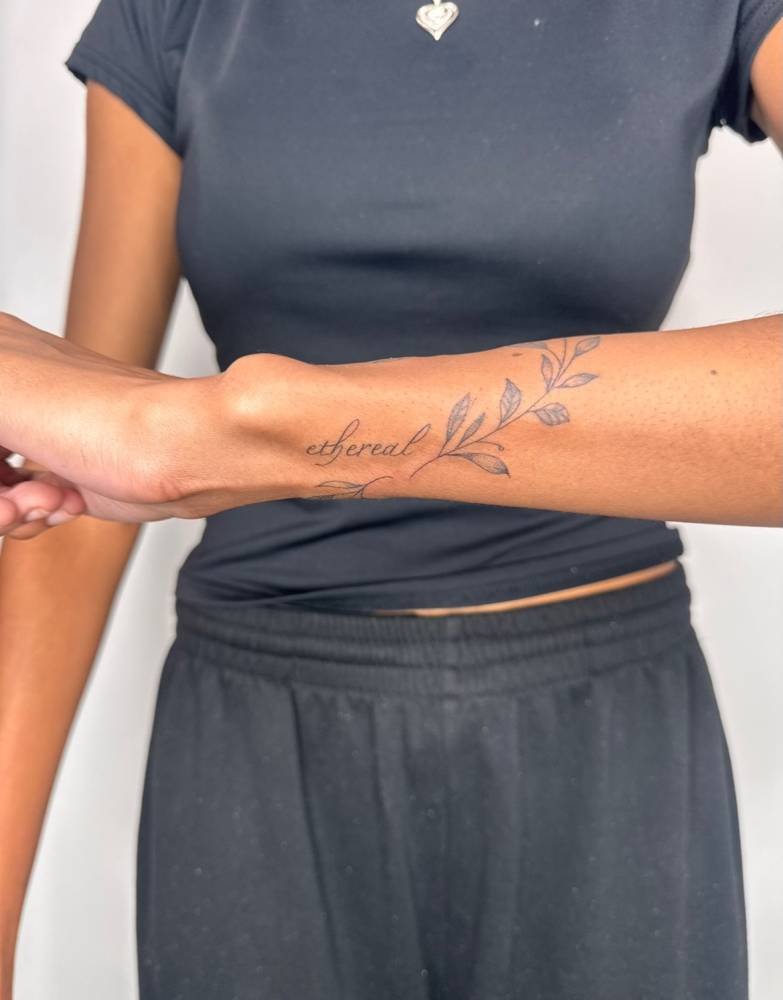 Script font word "ethereal" tattooed on the wrist.
