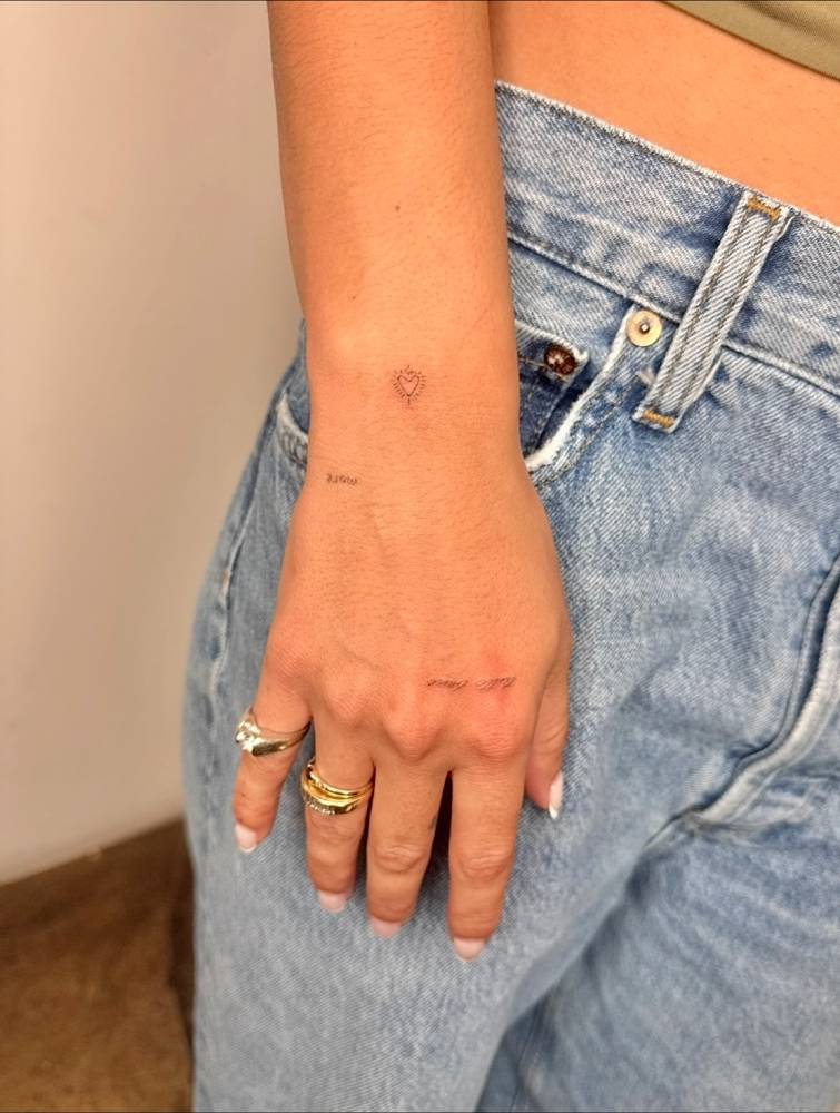 Minimalistic heart and words "tutto bene" tattooed on the wrist and hand.