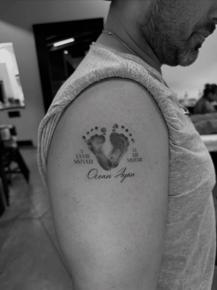 Baby footprint tattoo located on the upper arm.