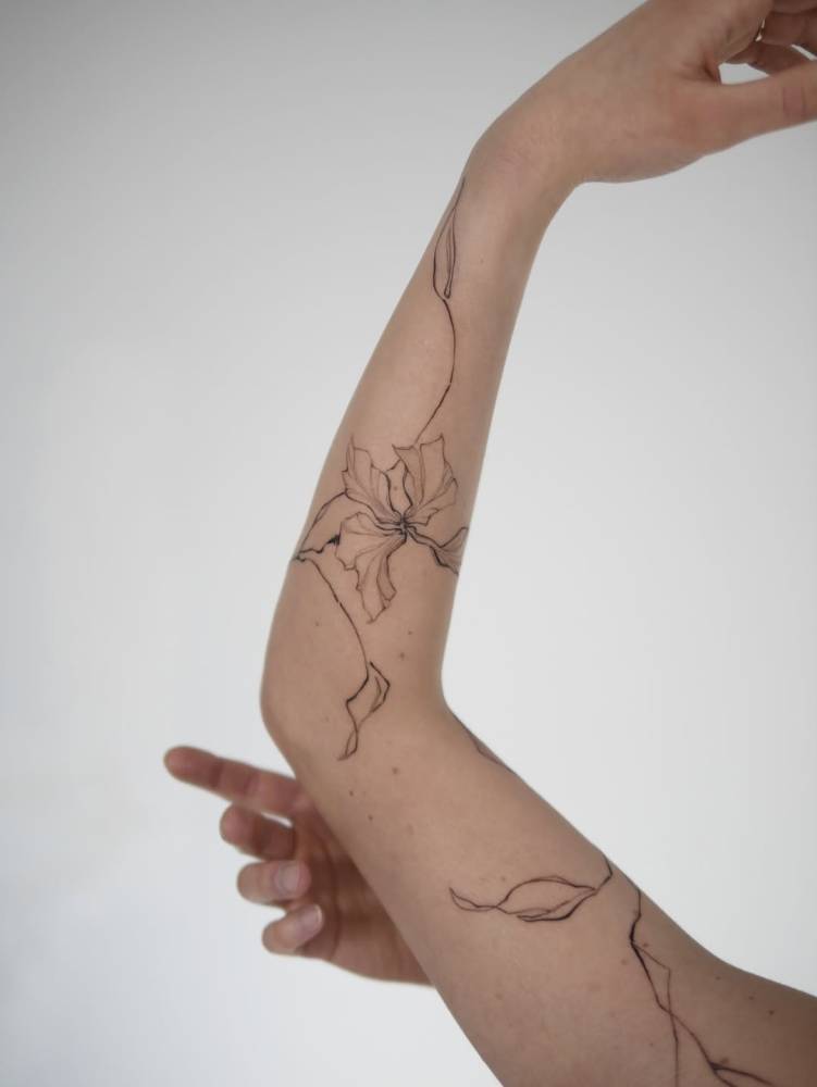 Iris flower tattoo in illustrative style located on the arm.
