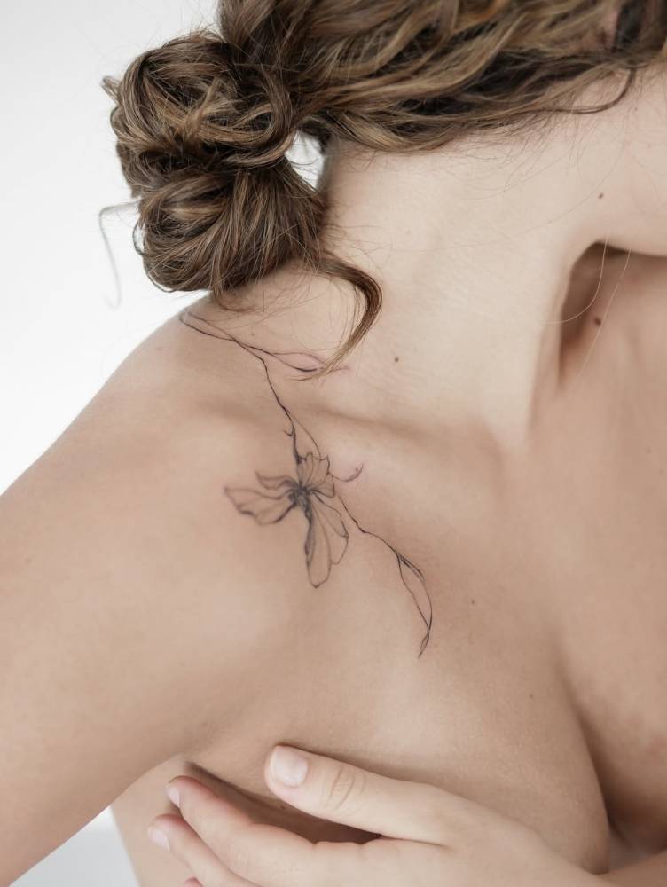 Illustrative style iris flower tattoo placed on the collarbone.