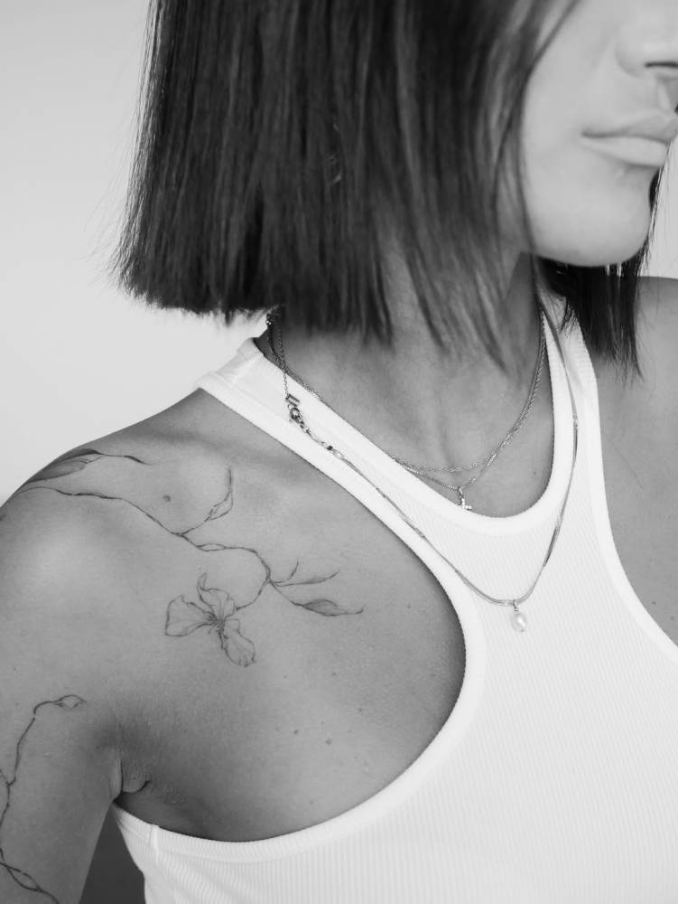 Flower tattoo in illustrative style placed on the collarbone.