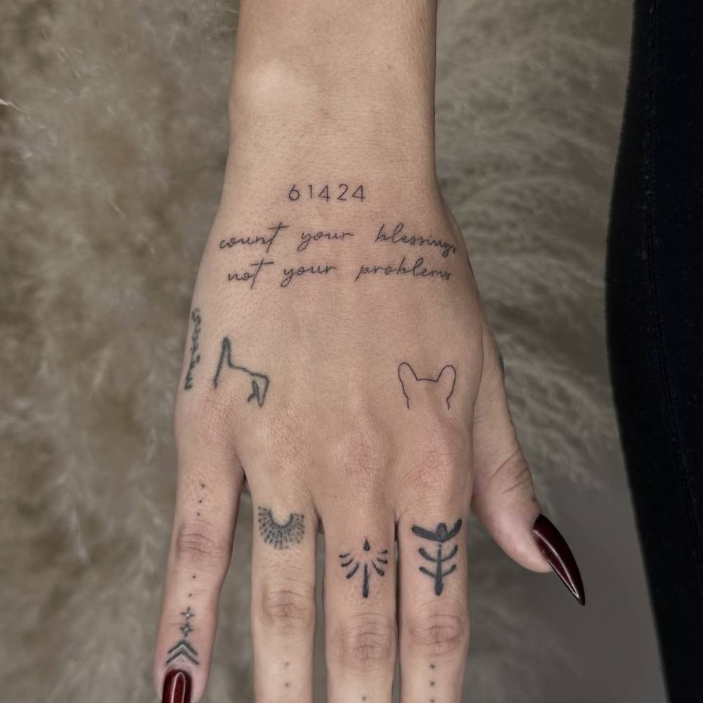"Count your blessings not your problems" and tiny dog ears tattooed on the hand.