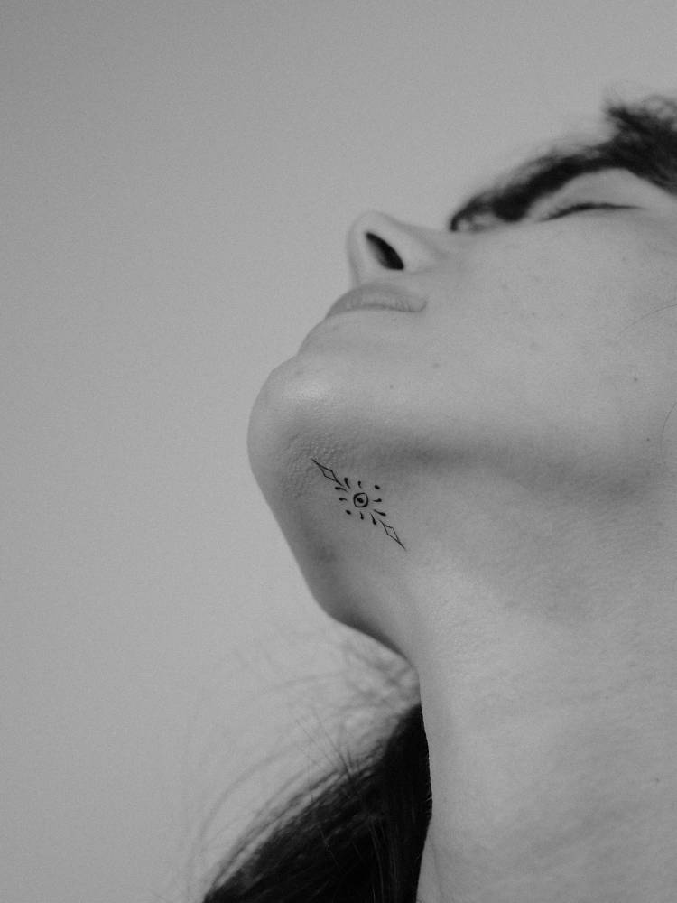 Minimalistic ornamental eye tattoo located on the neck.