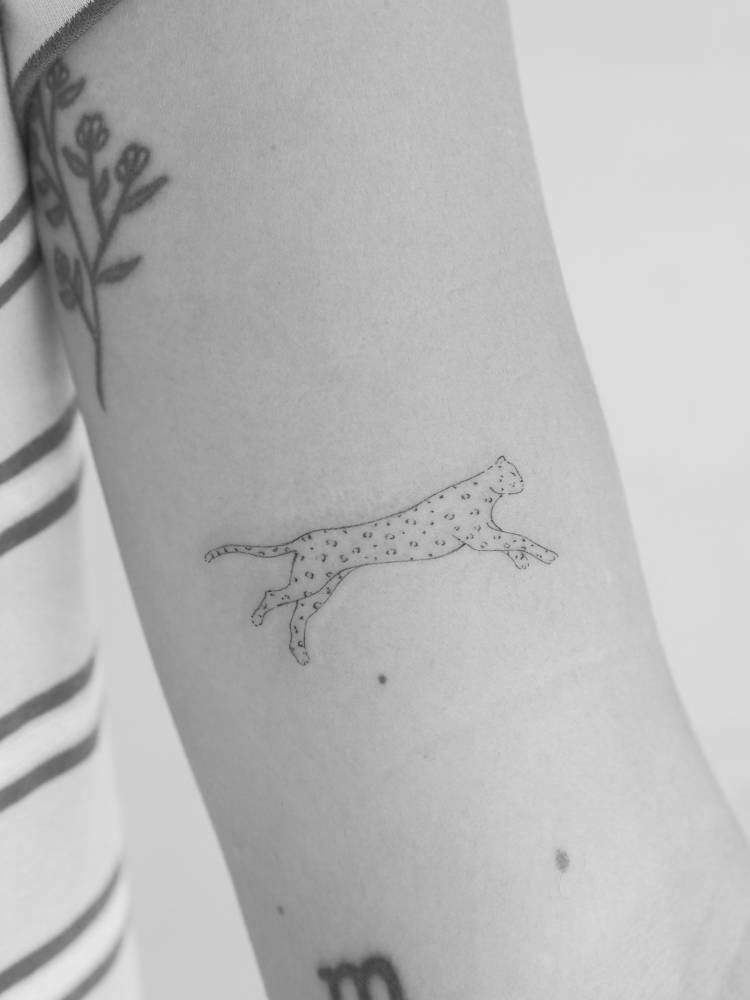 Little leopard tattoo in fine line style located on the inner arm.