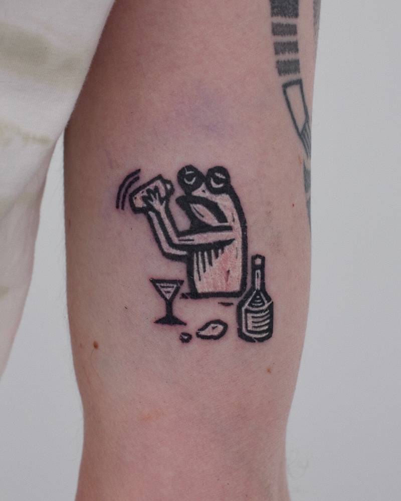 Pop art style bartending frog tattoo located on the inner arm.