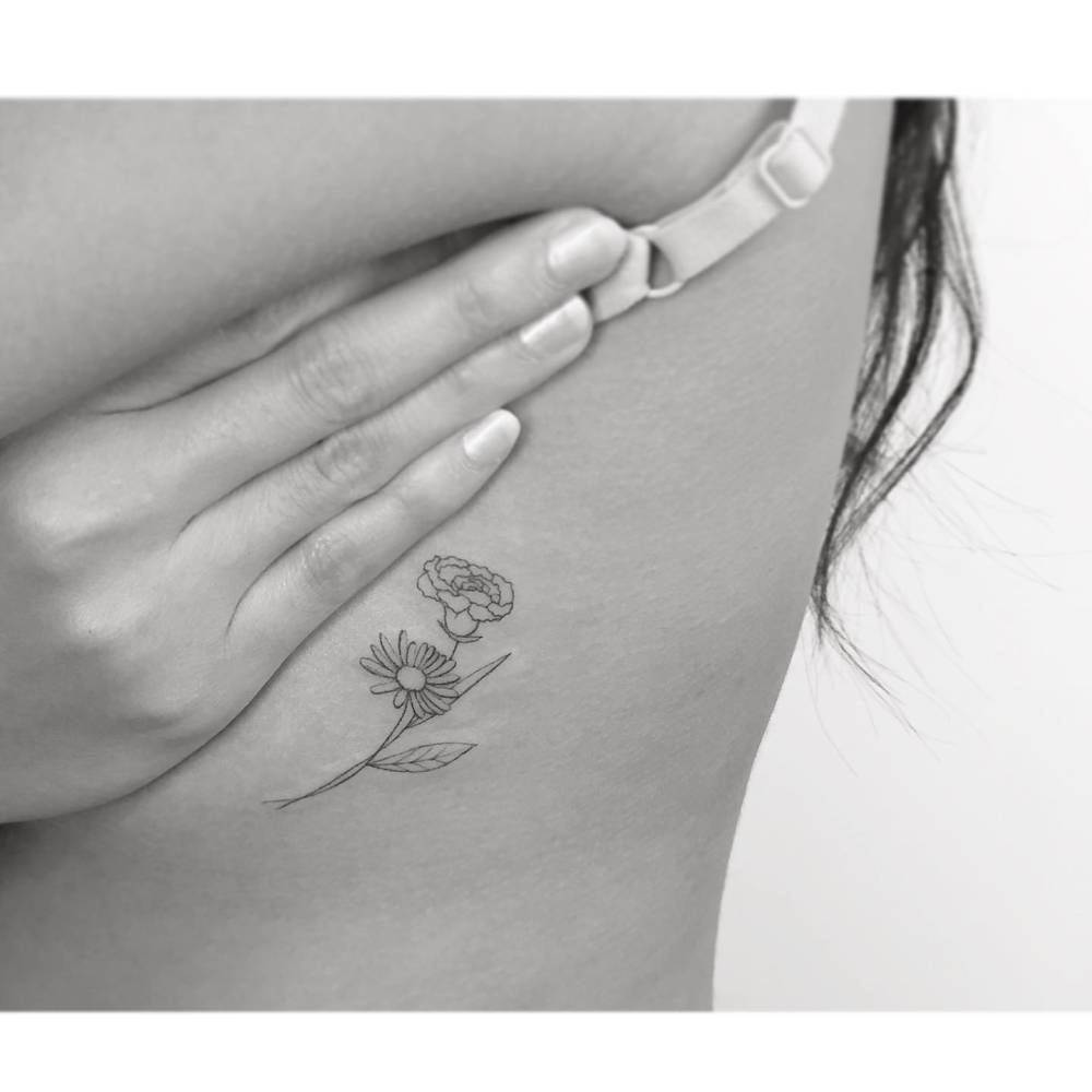 Carnation and daisy flower tattoo located on the side boob, fine line style.