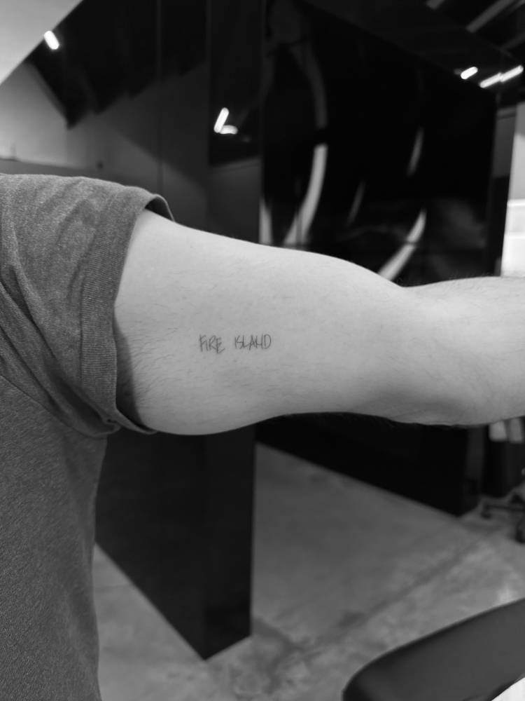 "Fire Island" lettering tattoo located on the inner arm.