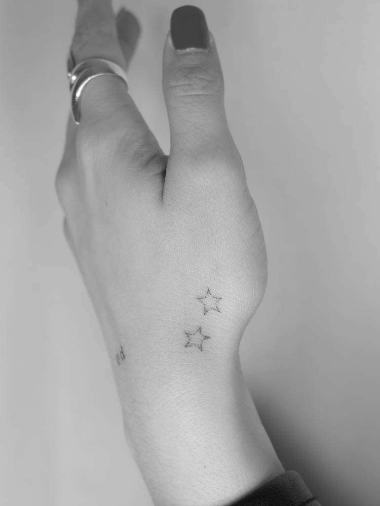 Minimalistic style star couple tattoo located on the hand.