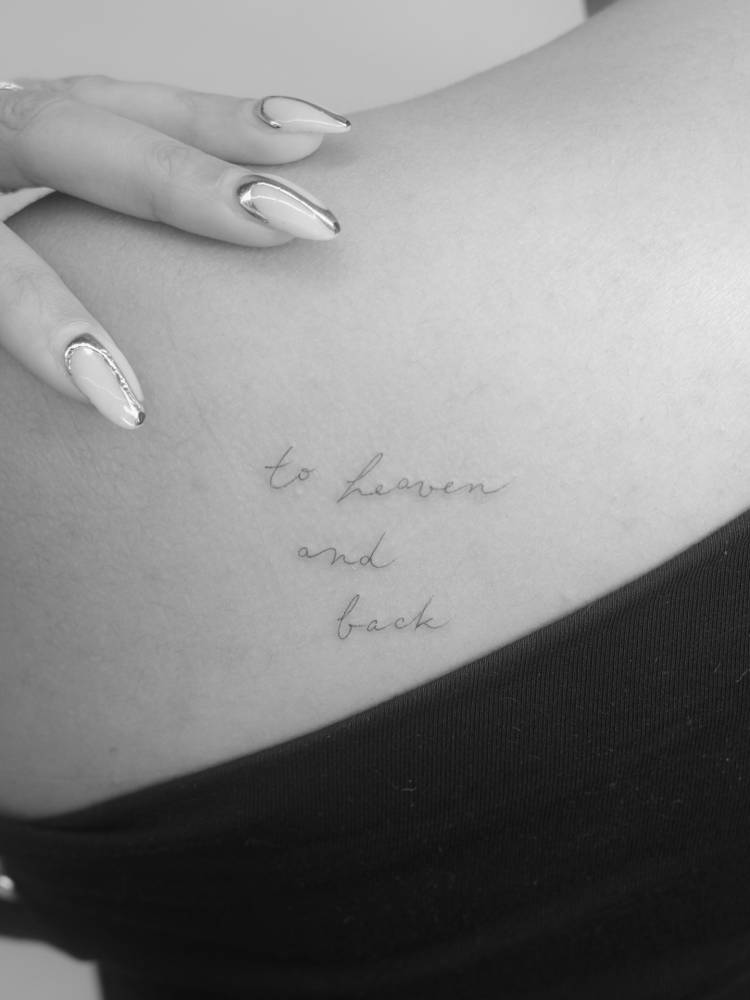 "To heaven and back" lettering tattoo placed on the shoulder blade.