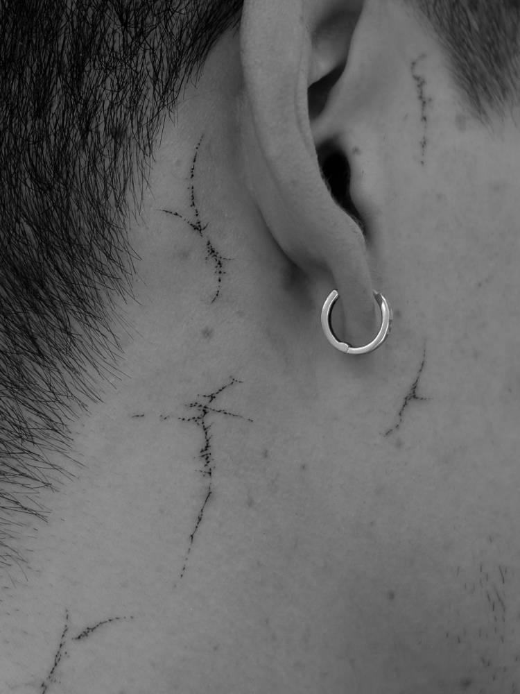 Little tribal designs tattooed behind the ear.