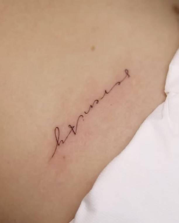Lettering tattoo of the word "serenity" located on the rib.