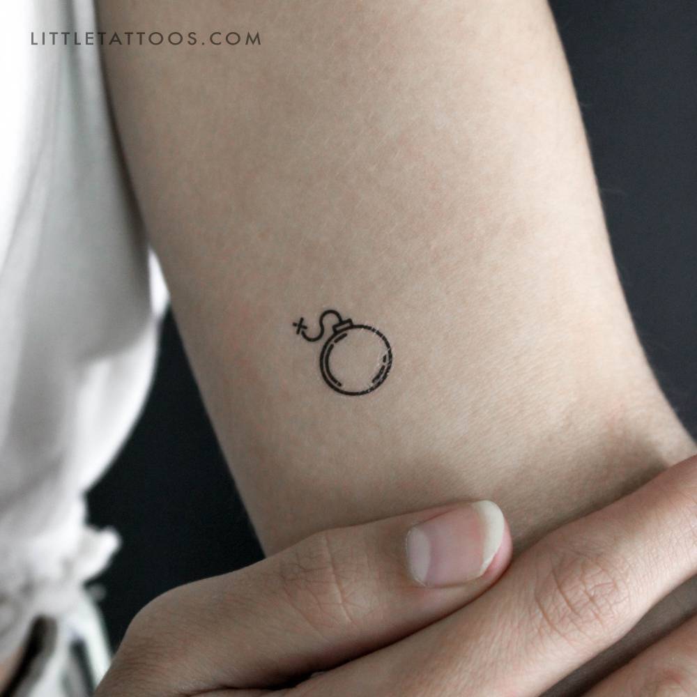 Tiny minimalistic bomb temporary tattoo placed on the inner arm.