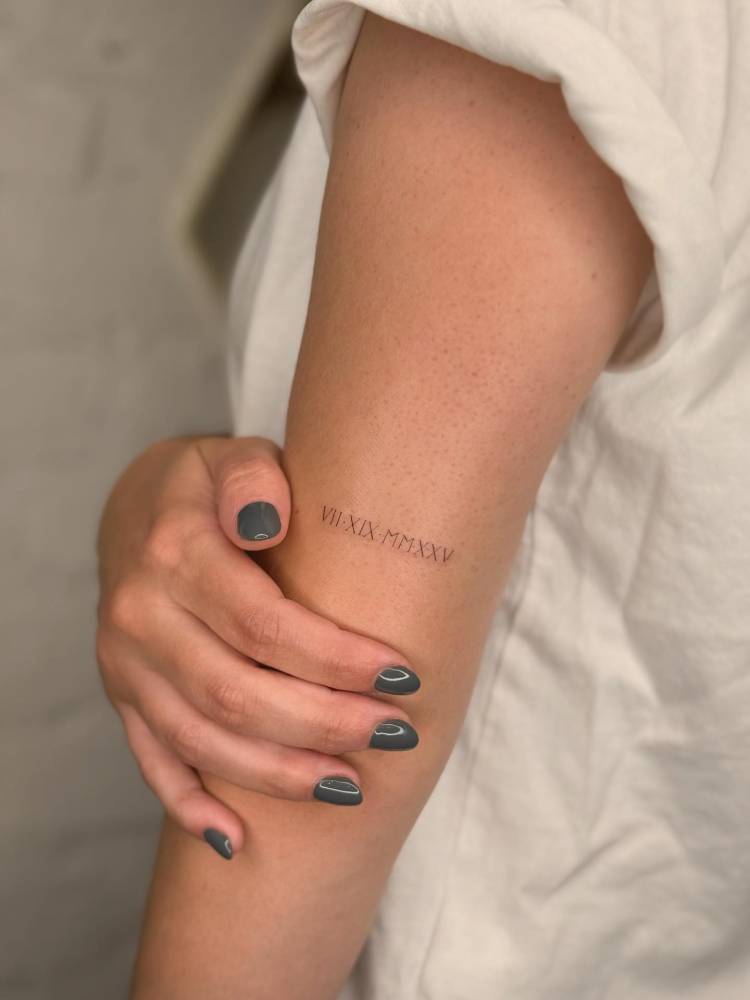 Date in roman numerals tattooed on the tricep.
