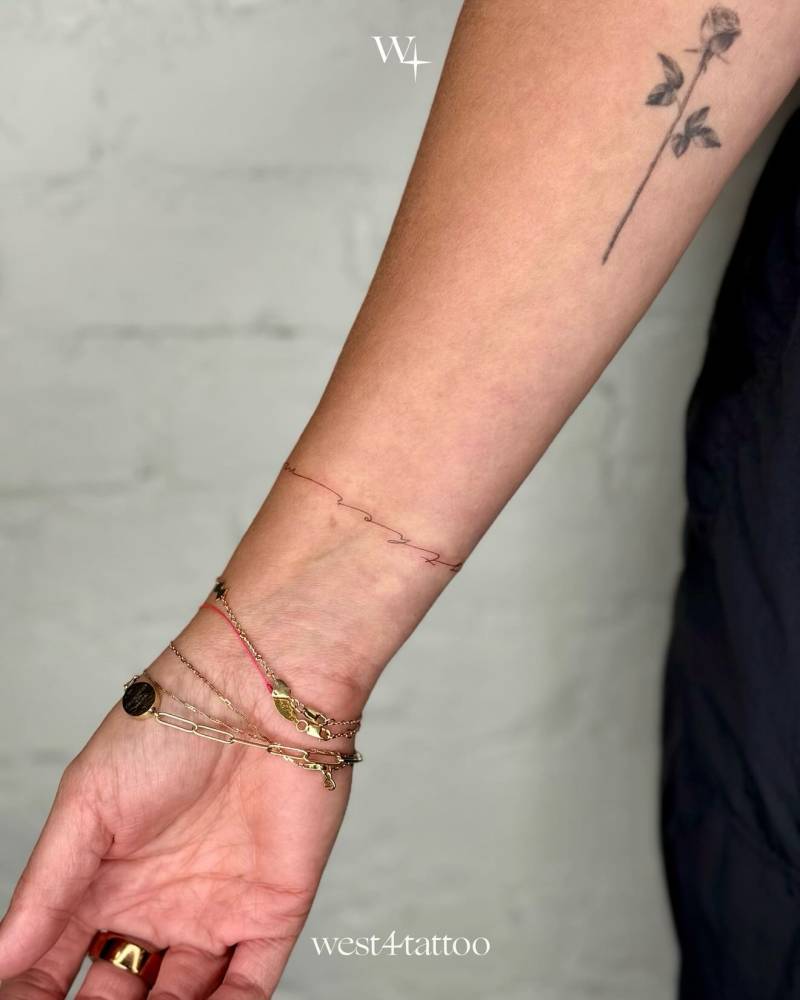 Lettering wristband tattoo in handwritten font.