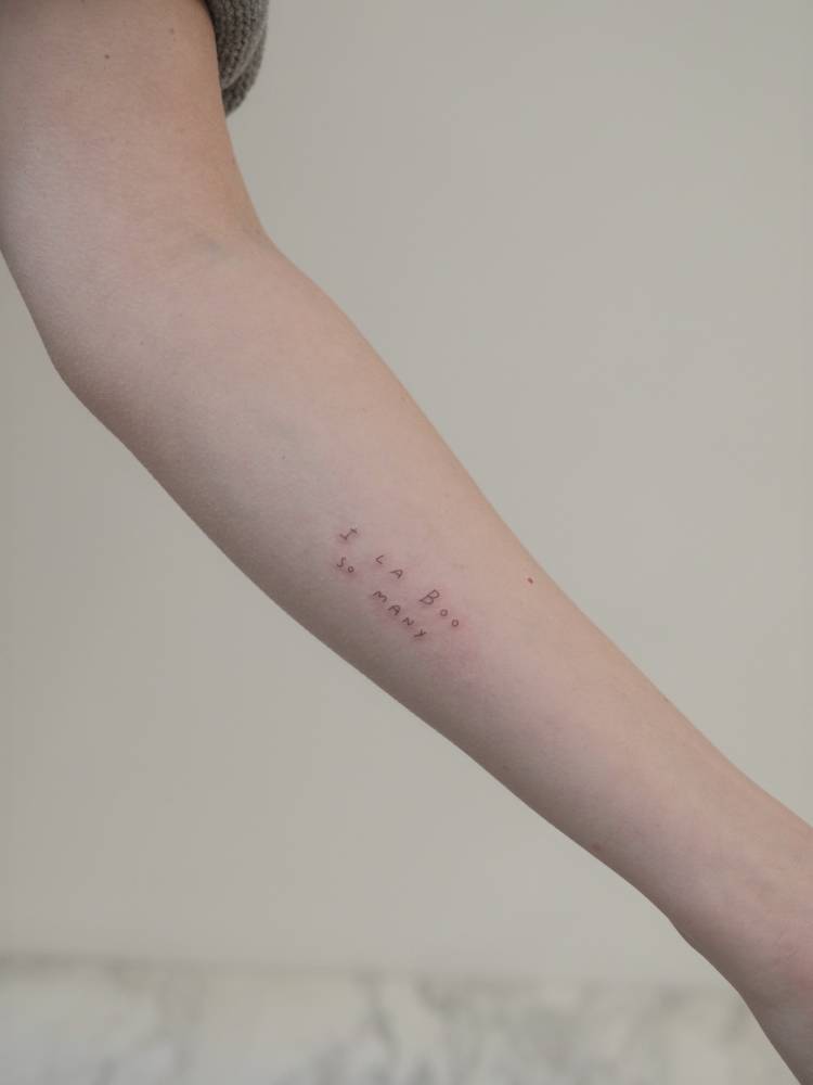 Handwritten lettering tattoo located on the inner forearm.