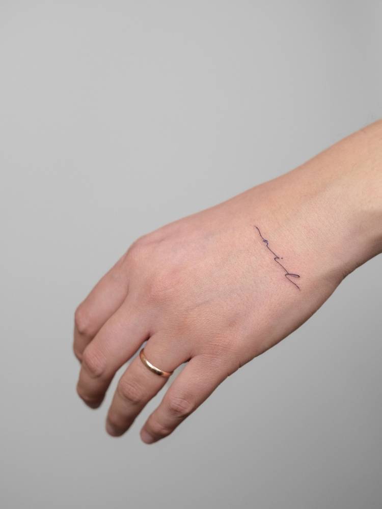Handwritten font name "Nil" tattooed on the hand.
