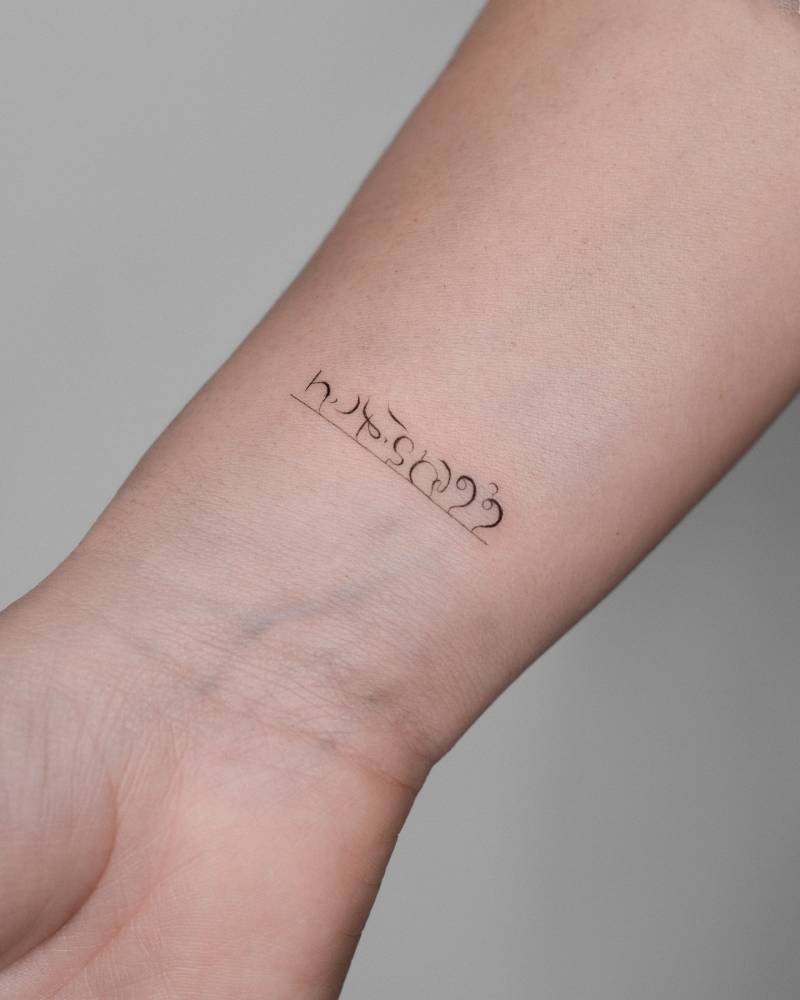 Elvish lettering tattoo located on the wrist.