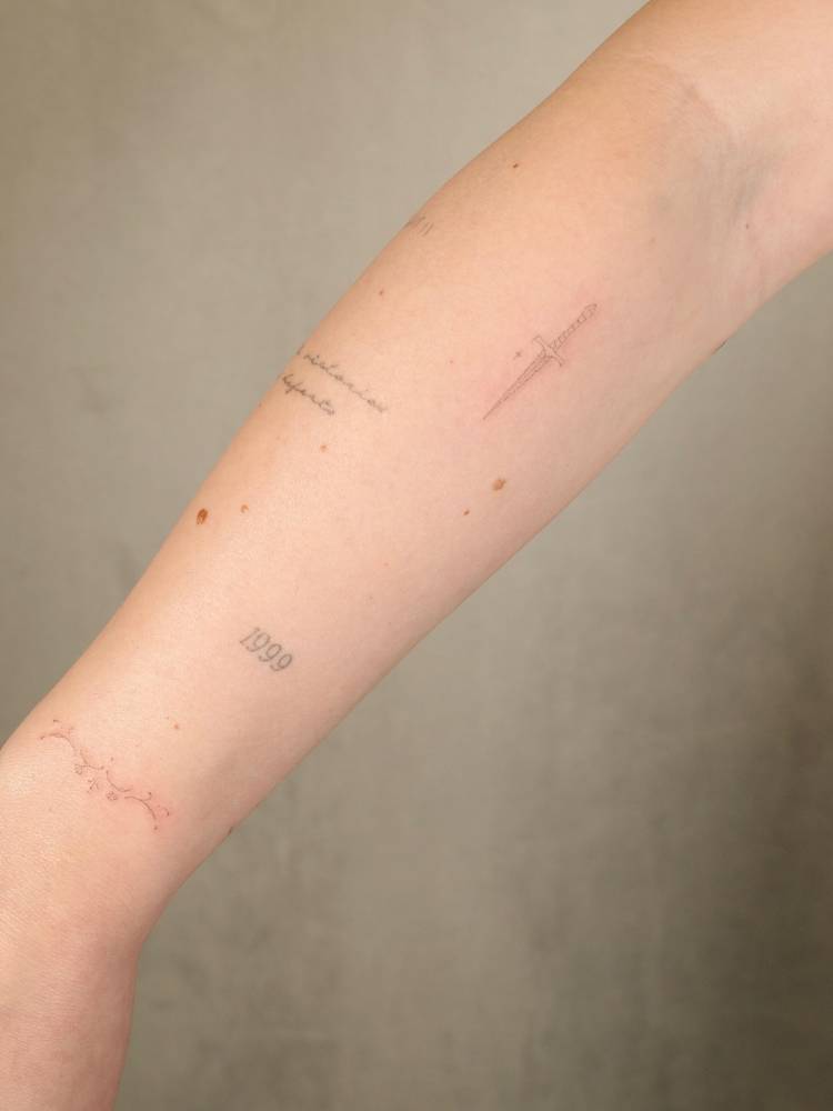 Dagger tattoo in fine line style located on the upper arm.