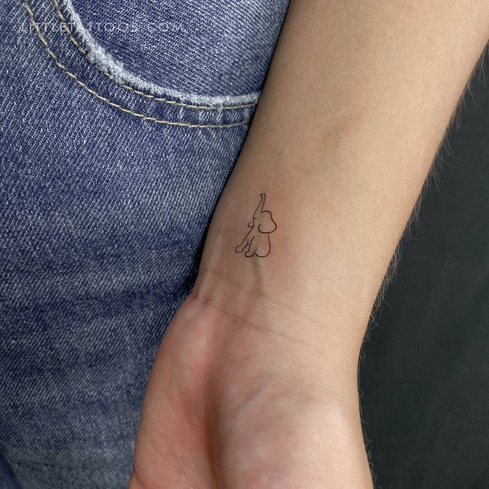 Fine line style little elephant temporary tattoo located on the wrist.