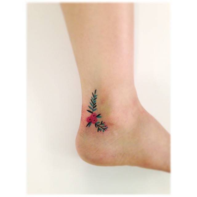 Flower branches tattooed on the ankle, illustrative style.
