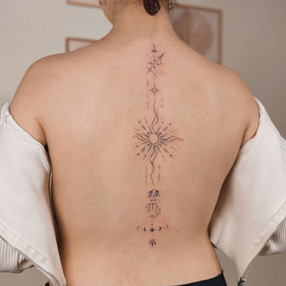 Ornamental sun and moon tattoo located on the spine.