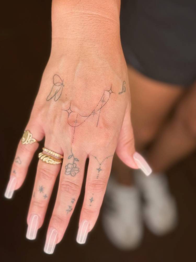 Ornamental stars tattoo located on the hand, done in fine line style.