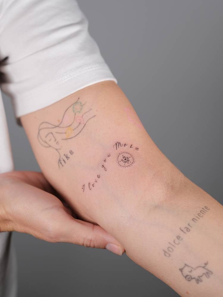 "I love you more" lettering tattoo located on the inner arm.