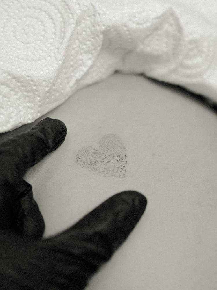 Illustrative style fingerprint heart tattoo located on the rib.