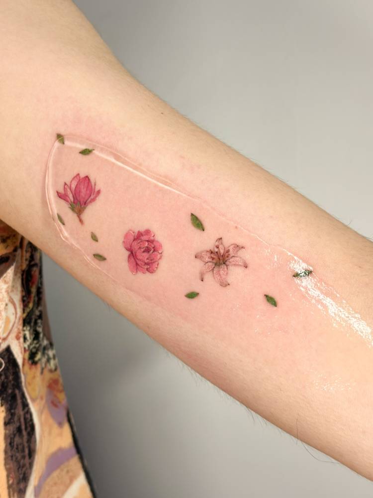 Magnolia, peony and lily tattoo located on the inner arm.
