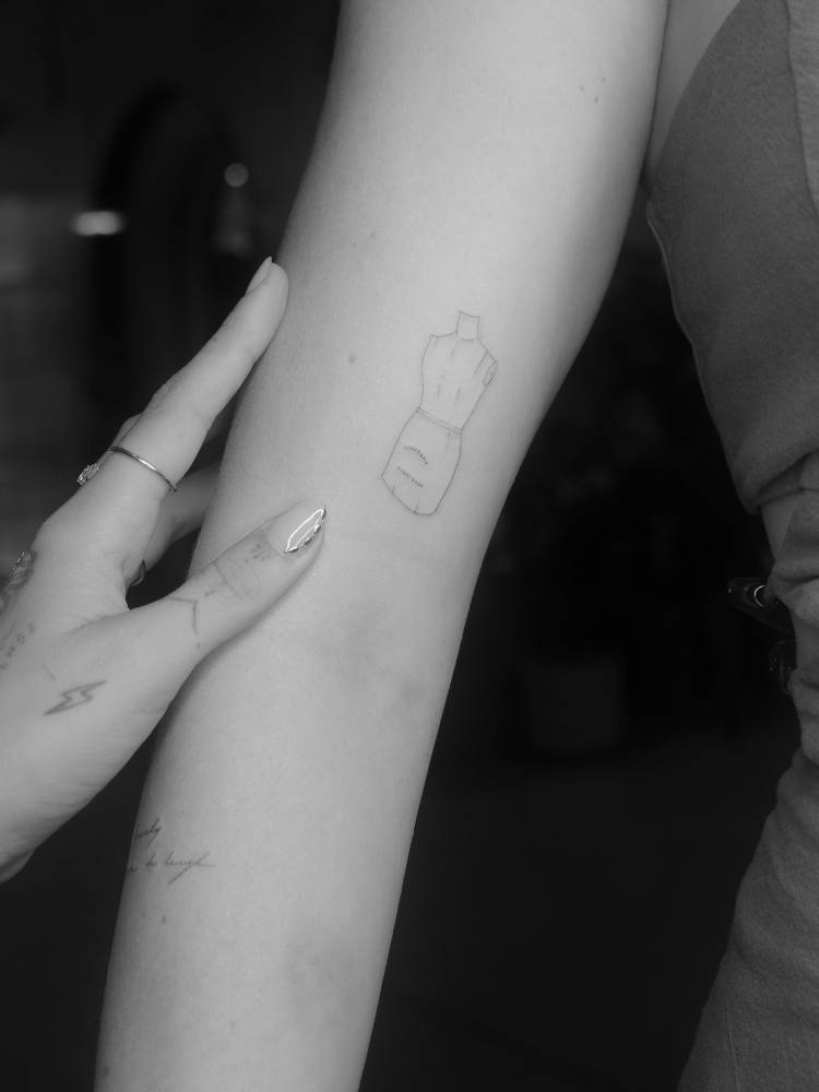 Mannequin tattoo in fine line style located on the bicep.