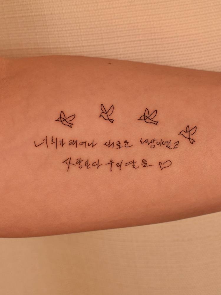 Flying birds and korean lettering tattoo located on the inner forearm.