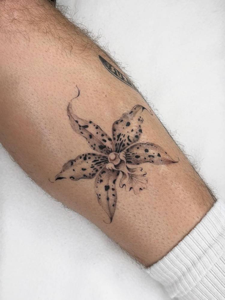 Illustrative style orchid tattoo located on the shin.