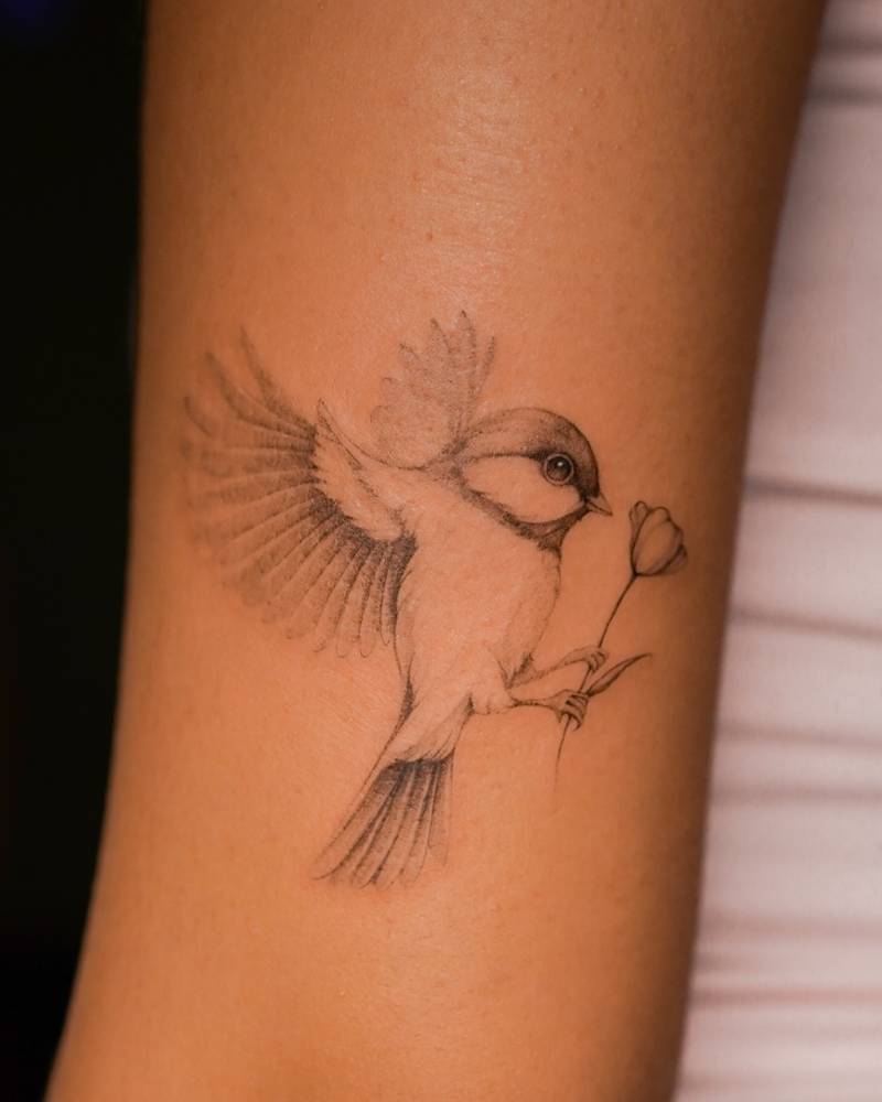 Sparrow tattoo located on the bicep, illustrative style.