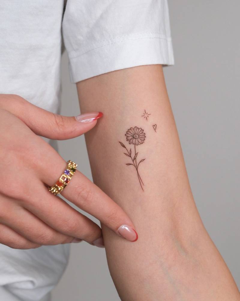 Daisy flower tattoo in fine line style placed on the inner arm.
