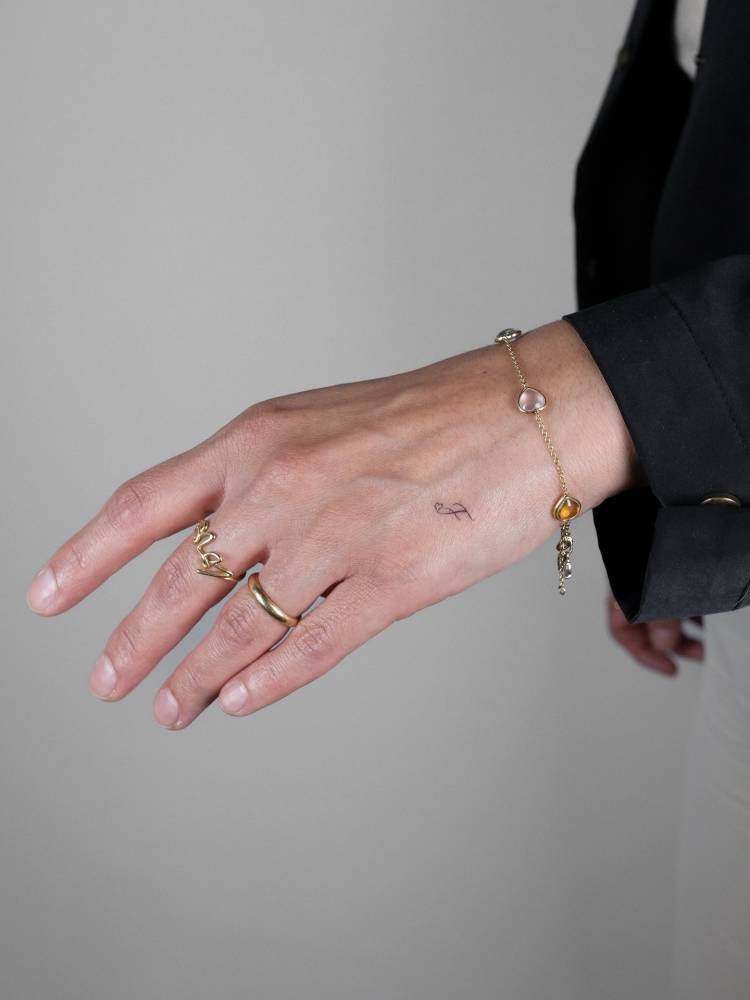 Tiny minimalistic letter "F" tattoo located on the hand.